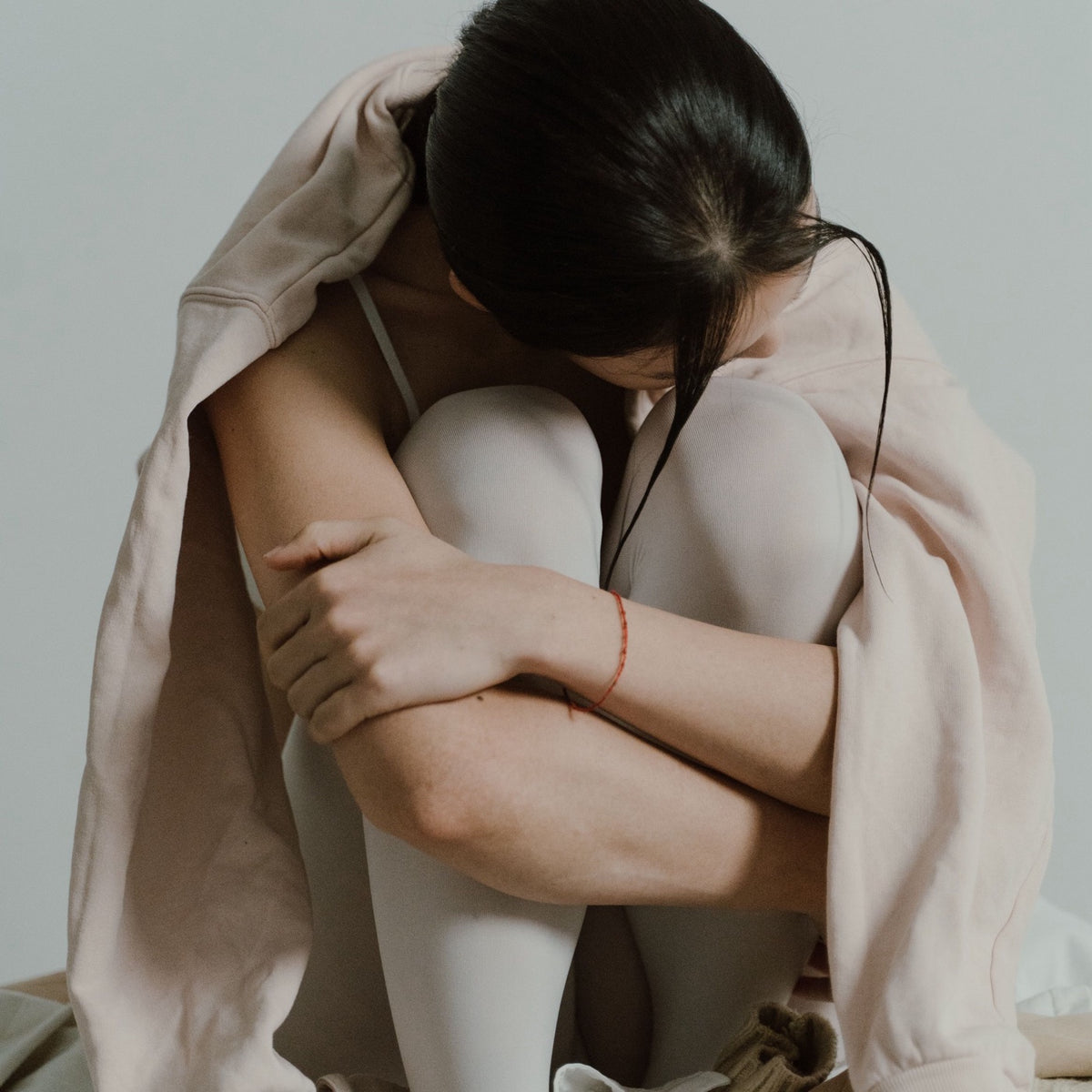 Jeune femme assise, genoux repliés contre elle, souffrant de règles douloureuses