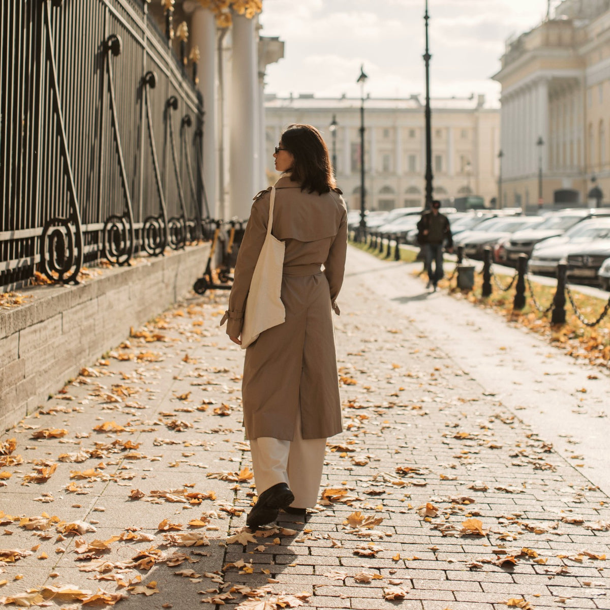 Femme de dos en manteau beige qui marche dans la rue, sa journée continue malgré ses règles Image